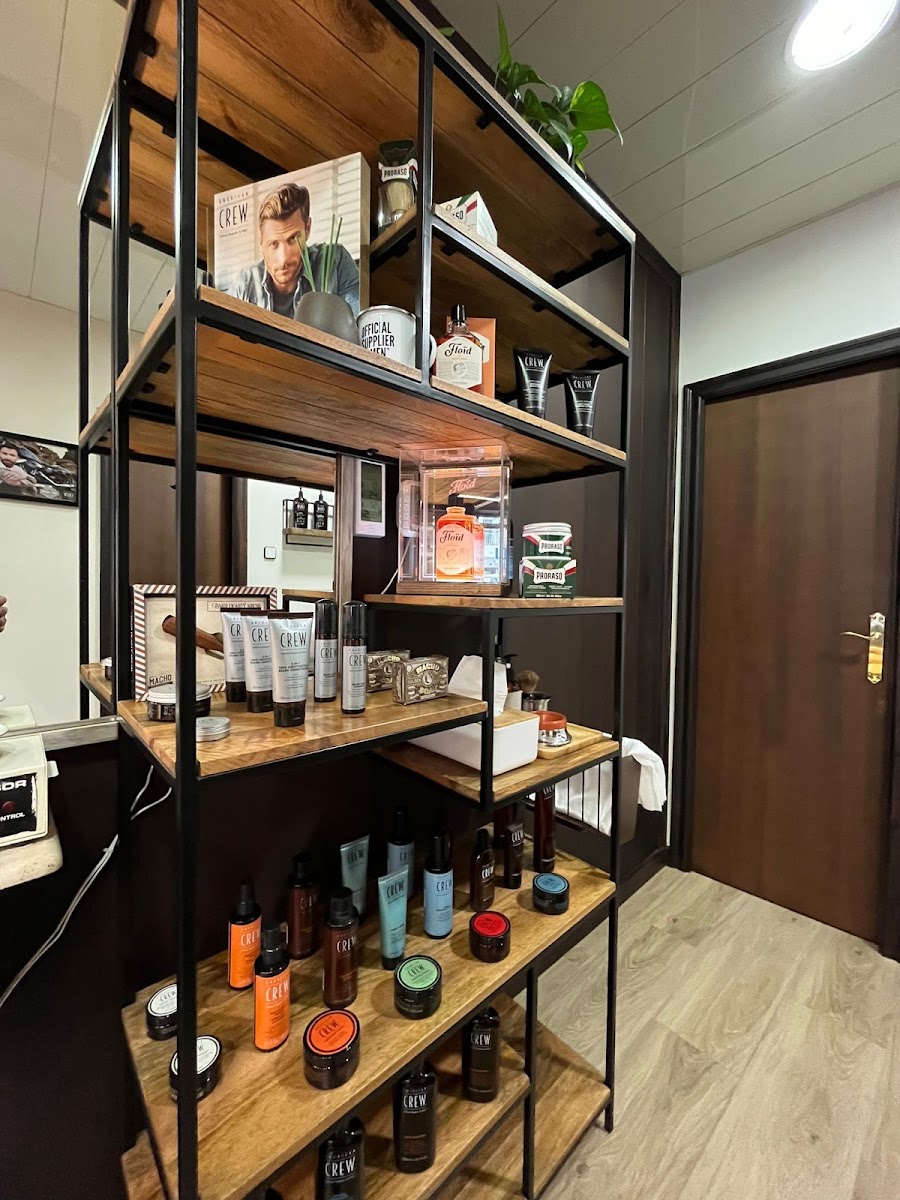 Mueble expositor de madera y acero negro con productos de afeitado, brochas y una vitrina iluminada.